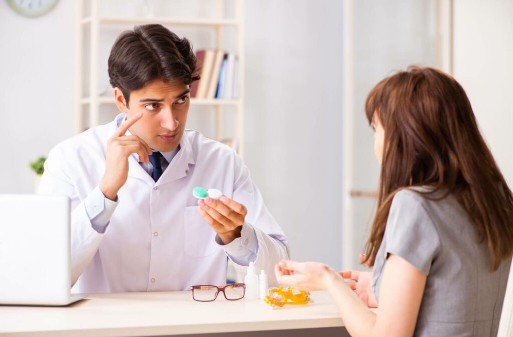 An eye doctor discusses proper contact lens wear and care with their patient during a contact lens exam.