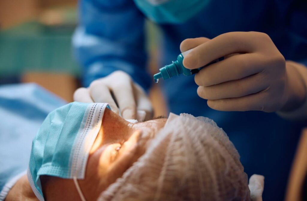 An ophthalmologist applying numbing eye drops to their patient, preparing them for cataract surgery.