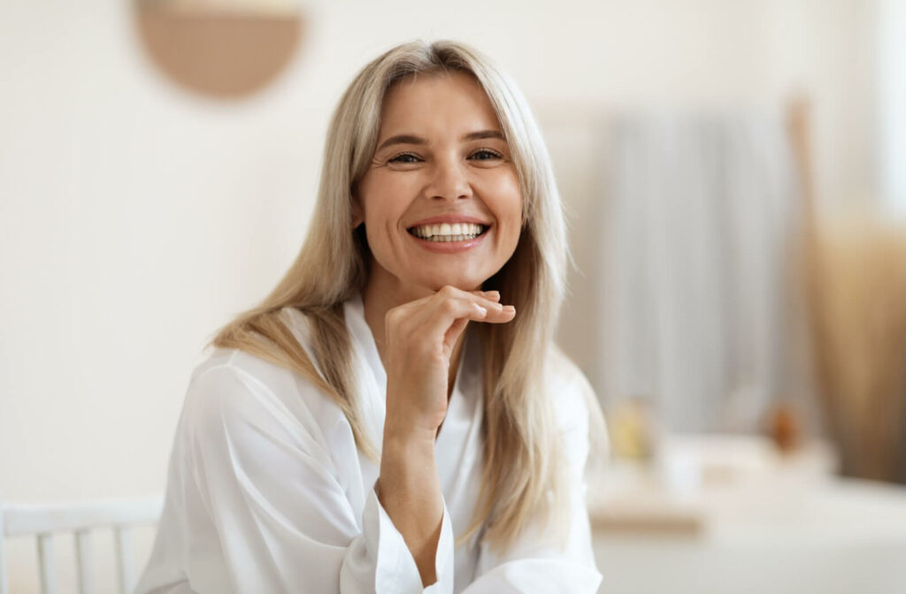 Smiling, youthful older blonde woman resting chin on hand.